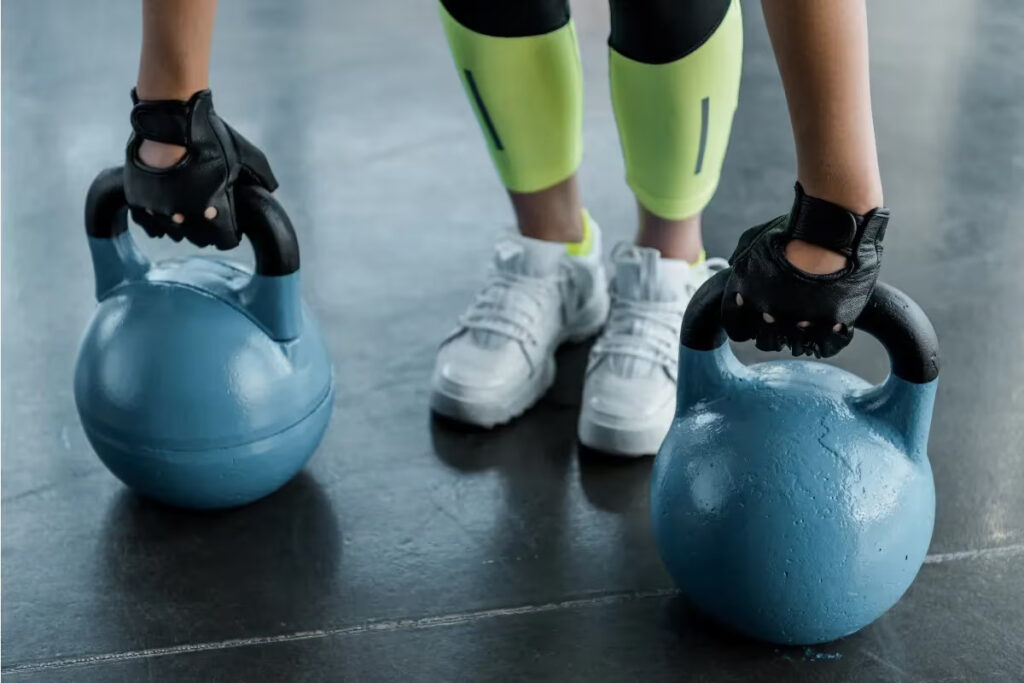 Athlet hält Kettlebells mit Handschuhen