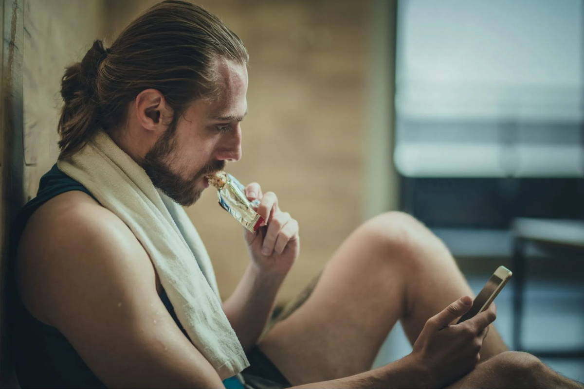 Athlete relaxing and eating bar