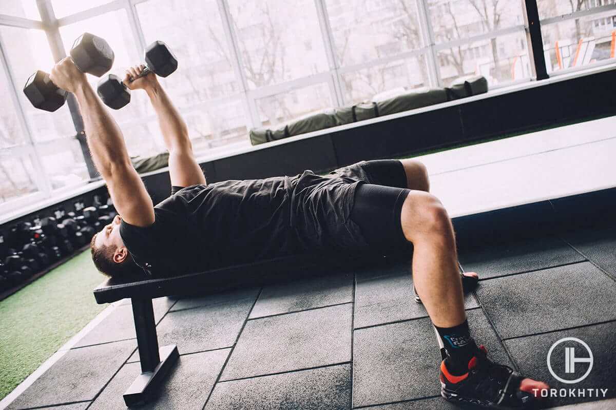 Athlete with dumbbells in gym