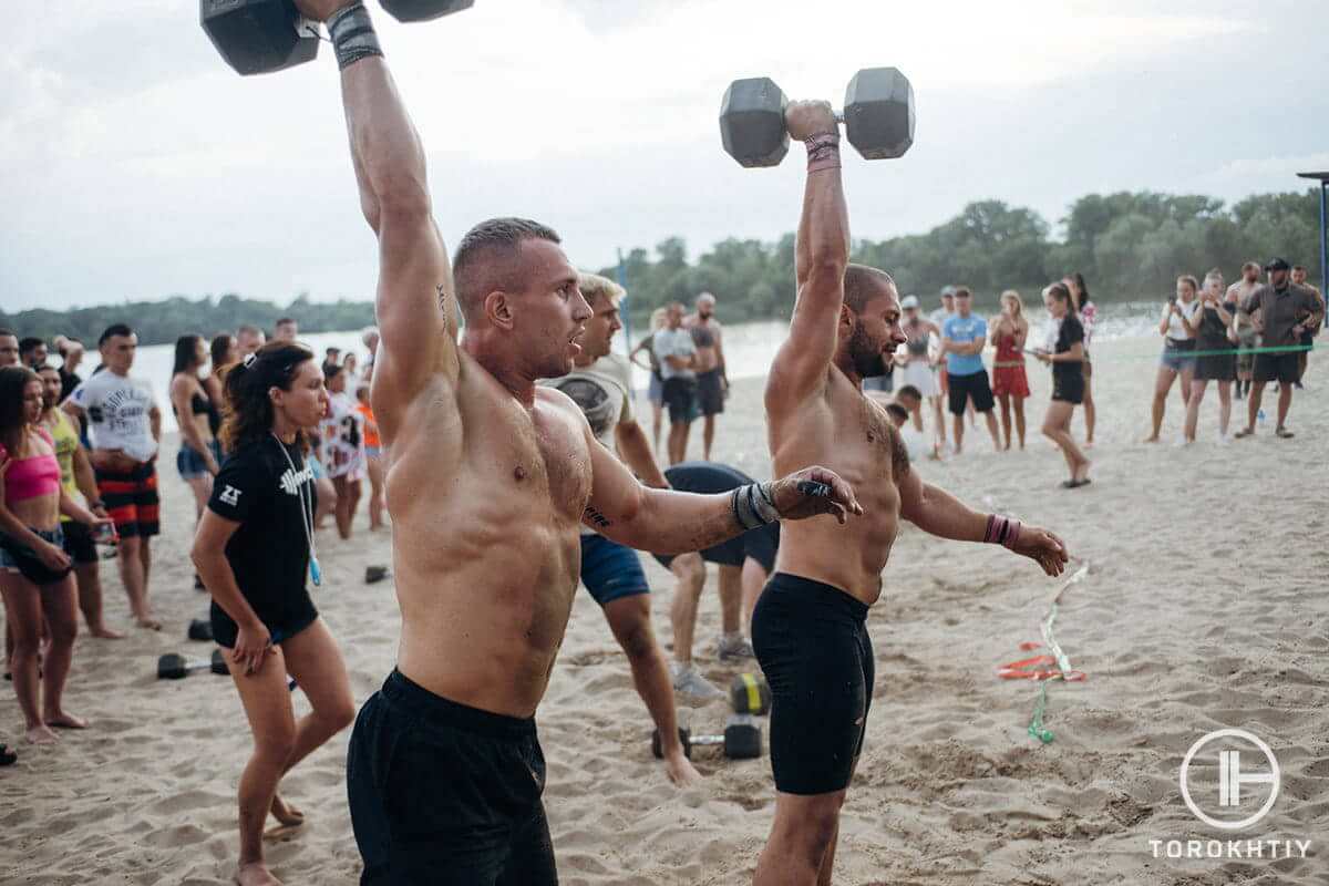 Athletes with dumbbells on beach