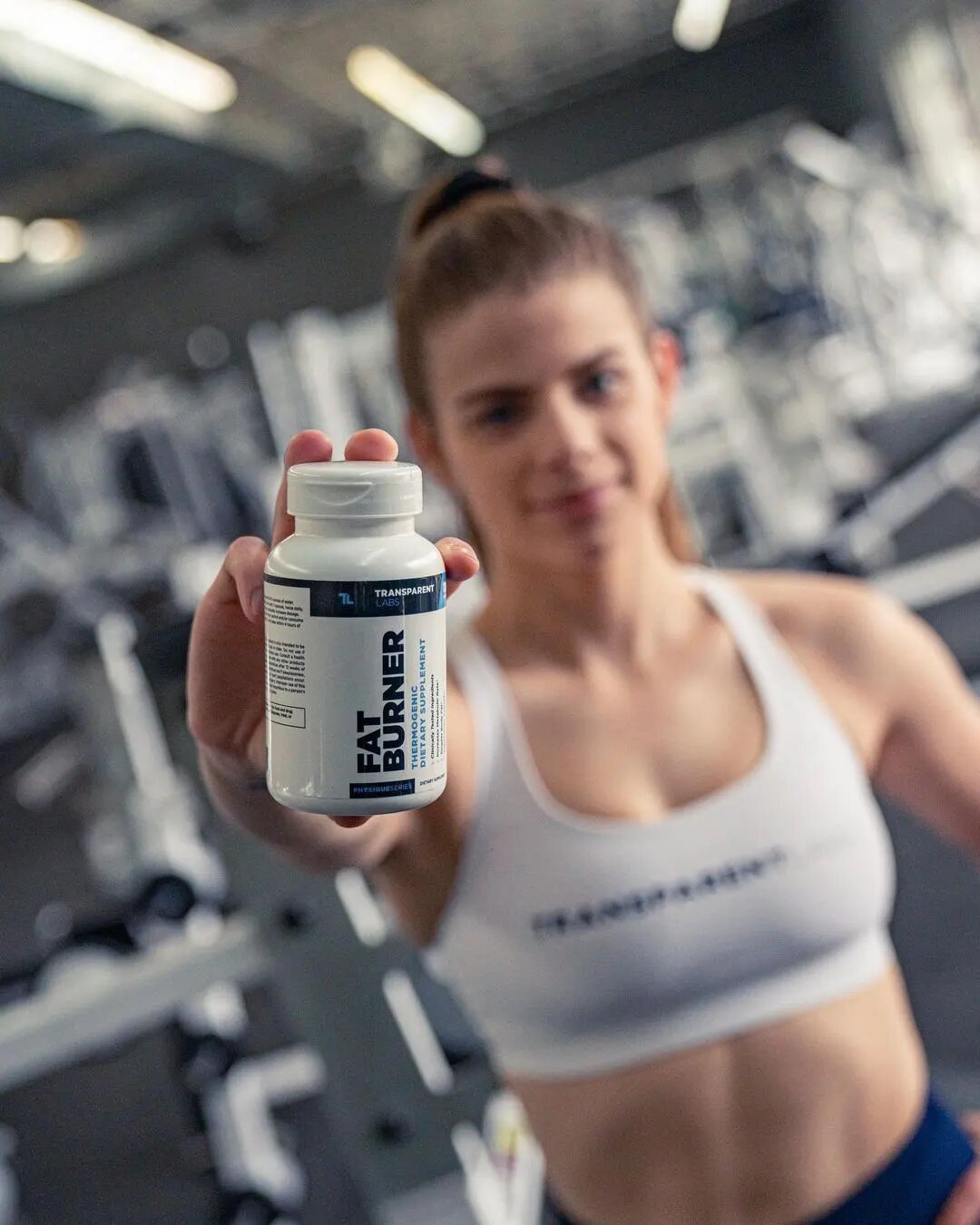 athlete woman holds fat burner bottle