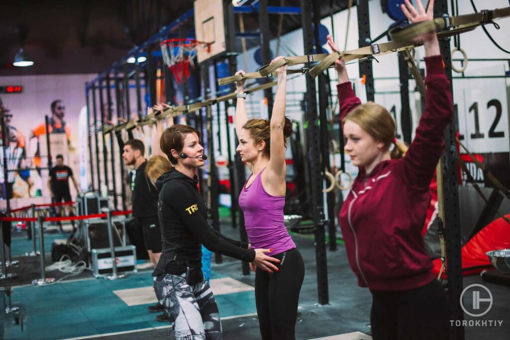 women exercise in gym with suspension trainer