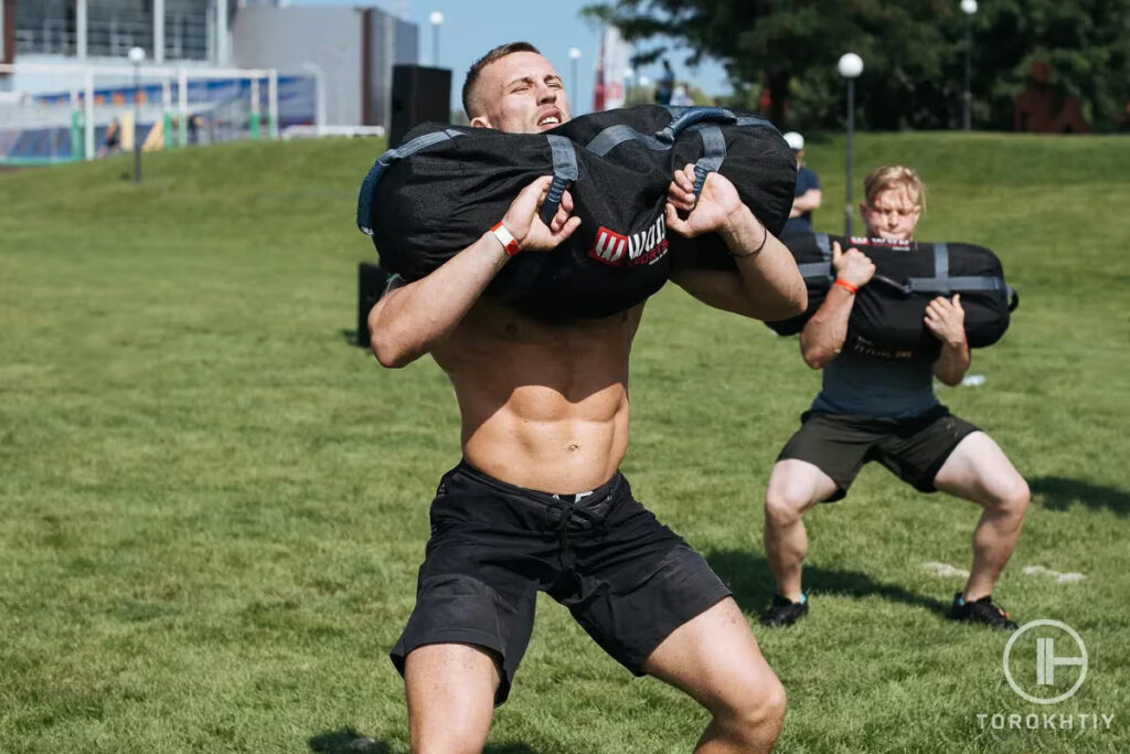 athletes doing workout with sandbags