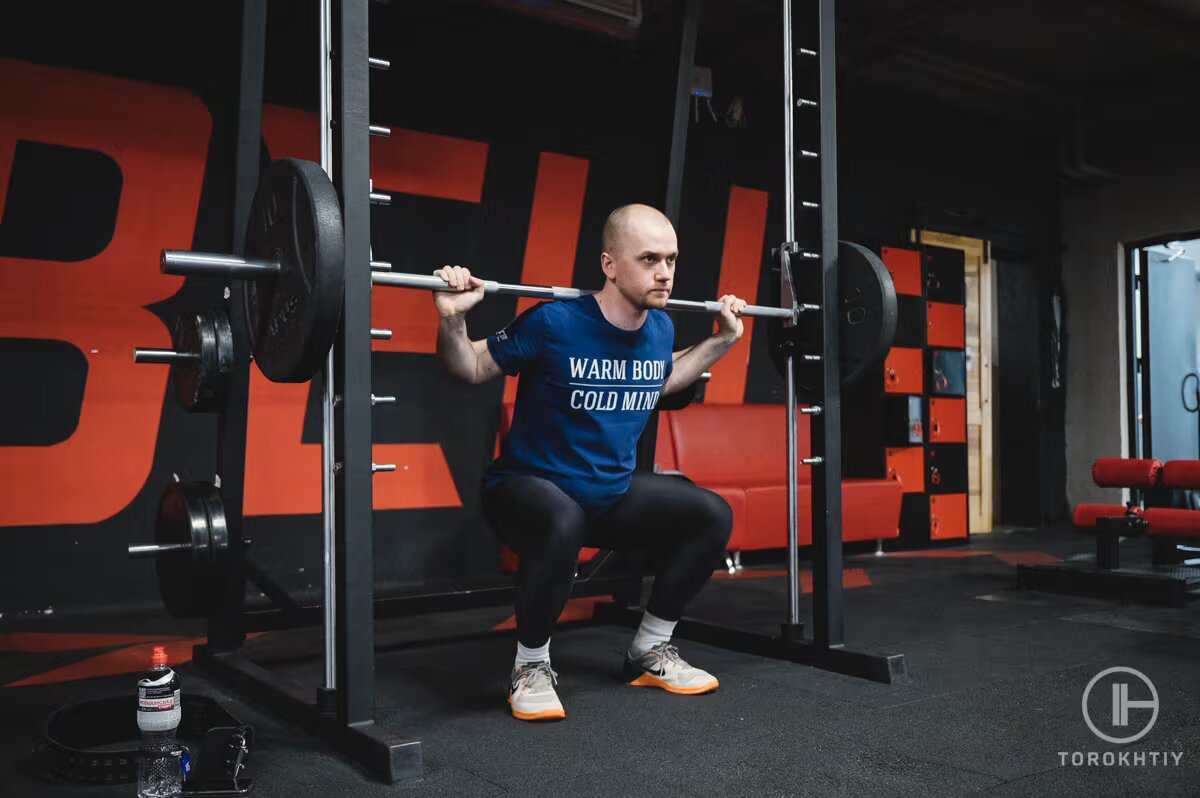 man workouts with barbell in gym