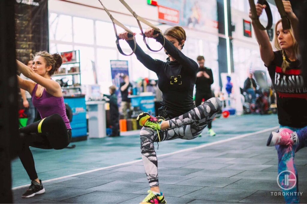 women work out in gym with suspension trainers