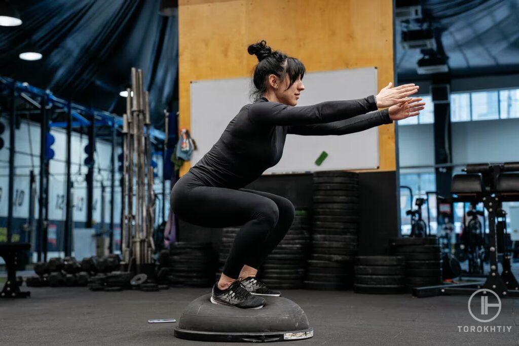 athlete woman doing exercise on bosu ball in gym