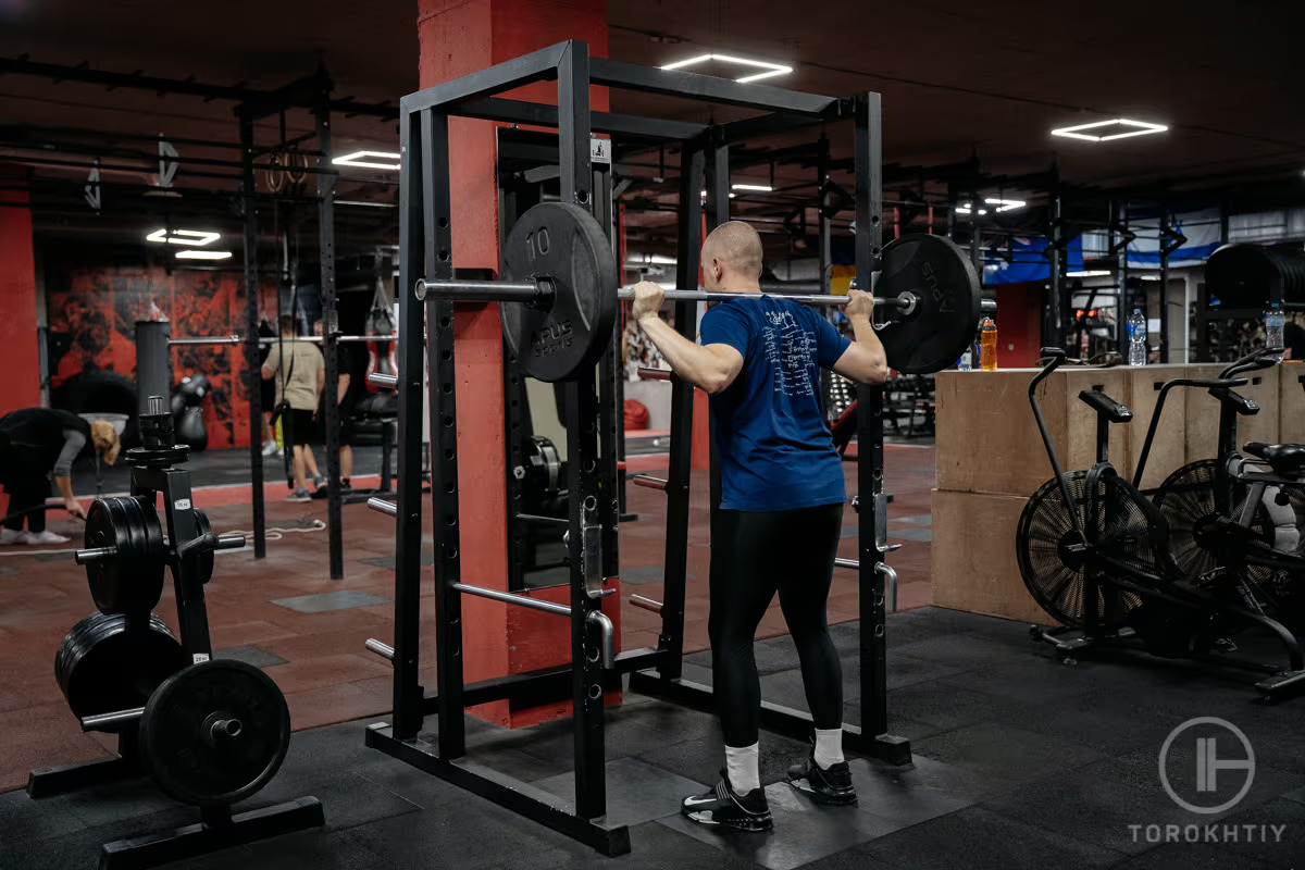 man exercises with barbell at gym