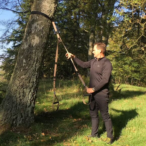 athlete and suspension trainer connected to tree