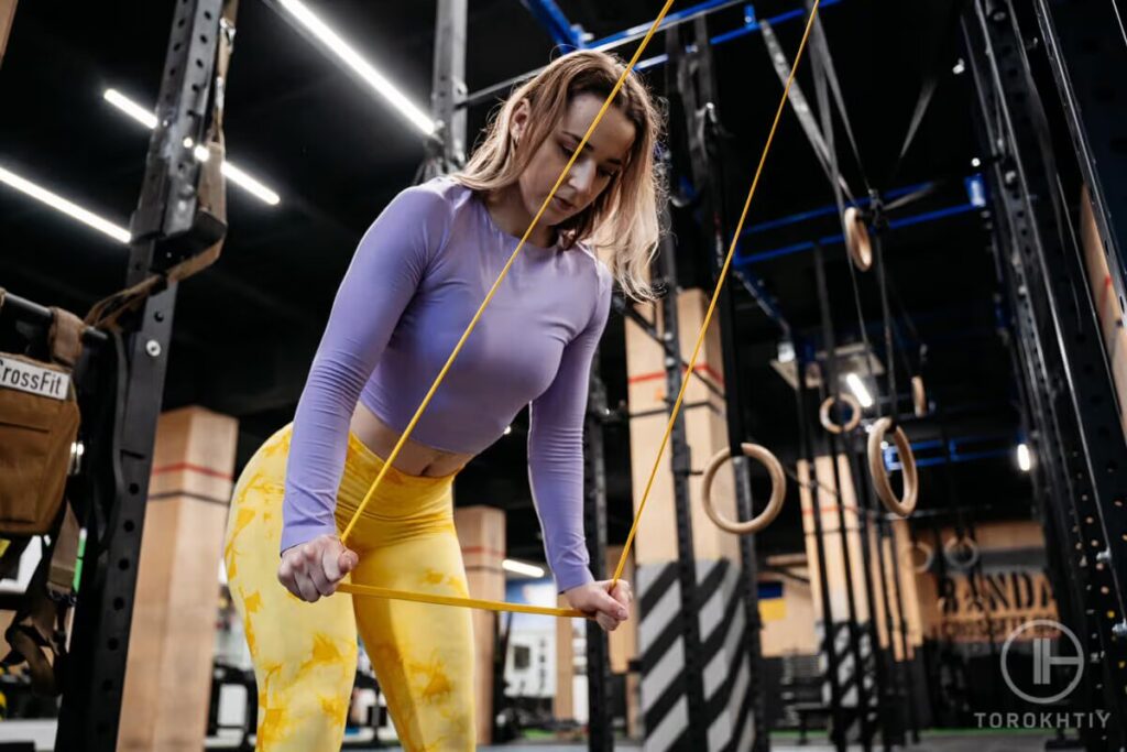 woman does exercise with resistance band in gym