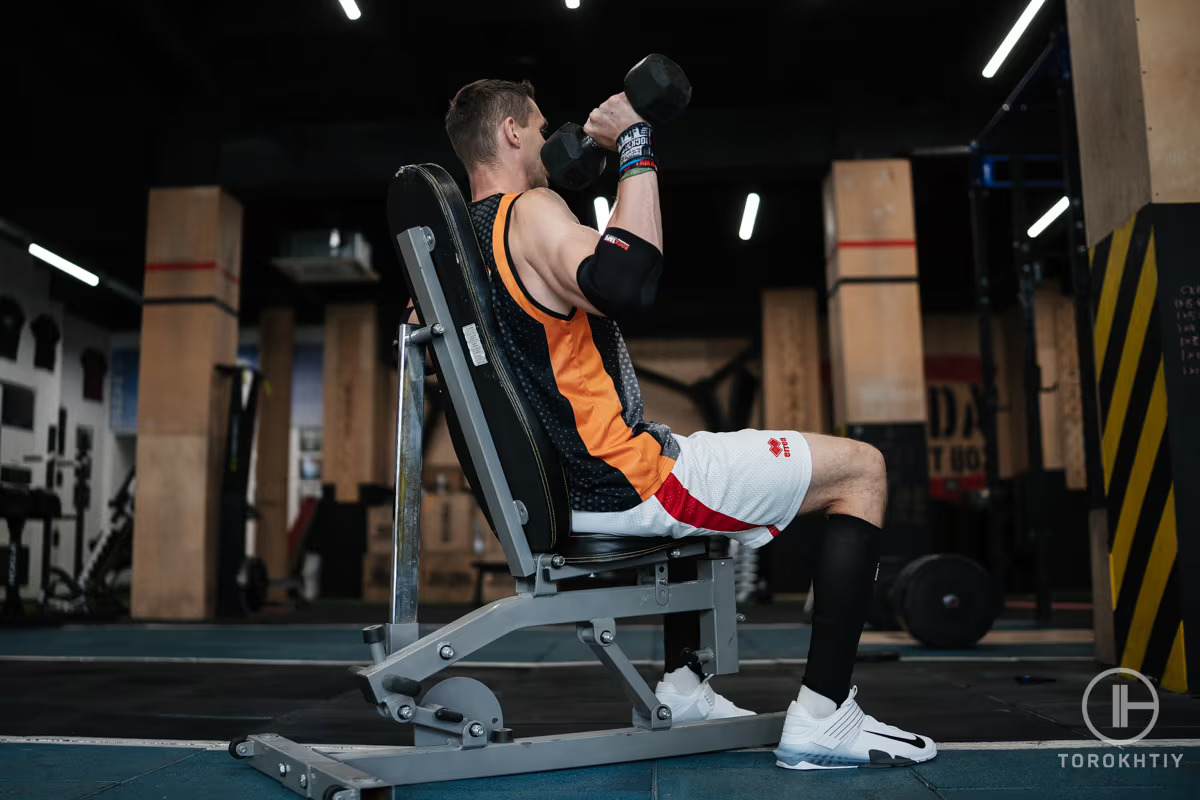 athlete working out with dumbbelles on bench