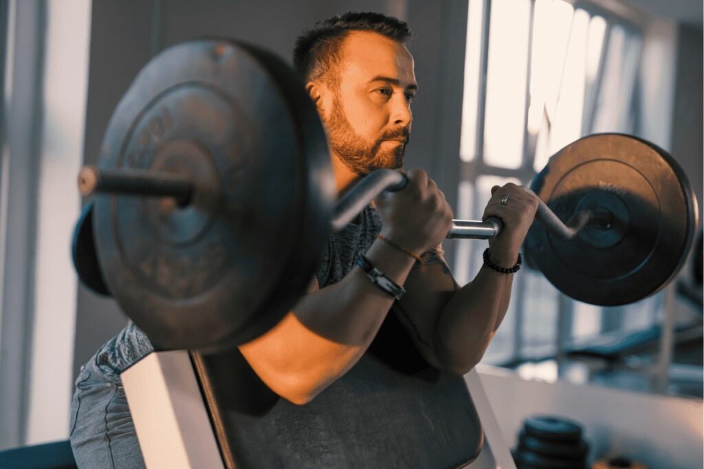 Man Lifting a Barbell on the Preacher Curl Bench