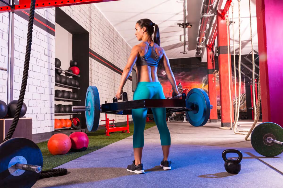 woman holds trap bar in gym